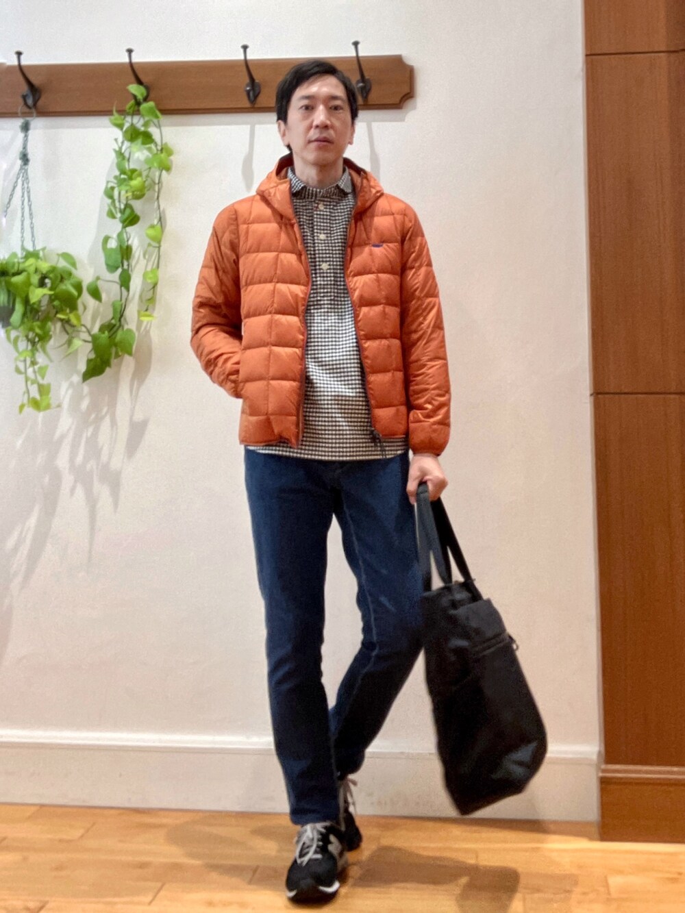 ブラック系のトートバッグ、ブルー系のデニムパンツ、オレンジ系のダウンジャケット/コートを着用したメンズの秋コーディネートの2枚目の写真