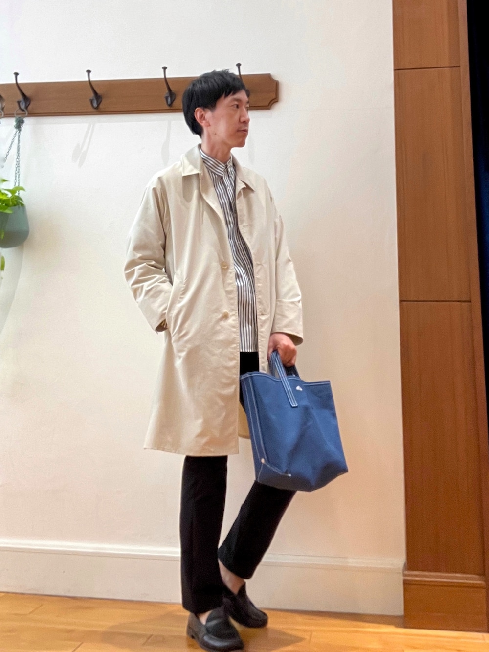 ホワイト系のステンカラーコート、グレー系のシャツ/ブラウス、レッド系のトートバッグを着用したメンズの春コーディネートの2枚目の写真