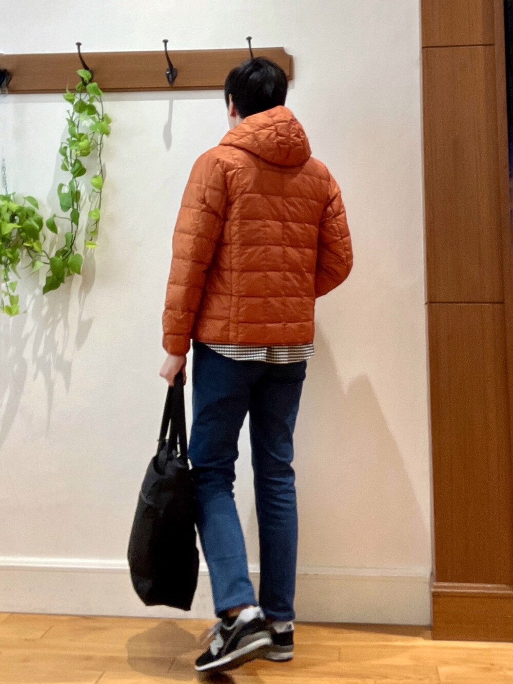 ブラック系のトートバッグ、ブルー系のデニムパンツ、オレンジ系のダウンジャケット/コートを着用したメンズの秋コーディネートの4枚目の写真