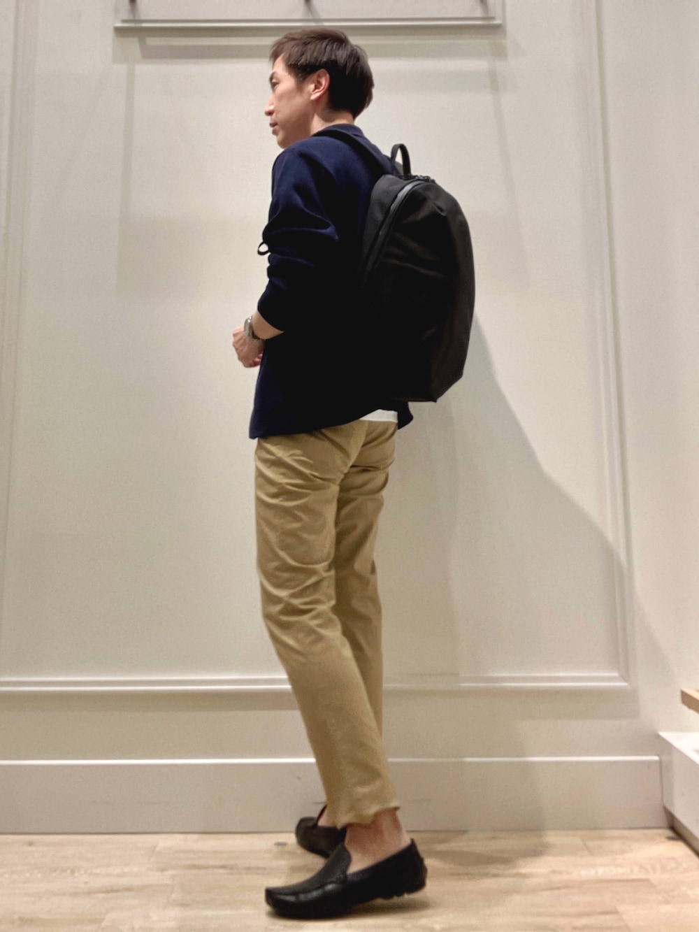 ベージュ系のチノパンツ、ブラック系のバックパック/リュック、ブルー系のカーディガン/ボレロを着用したメンズの冬コーディネートの5枚目の写真