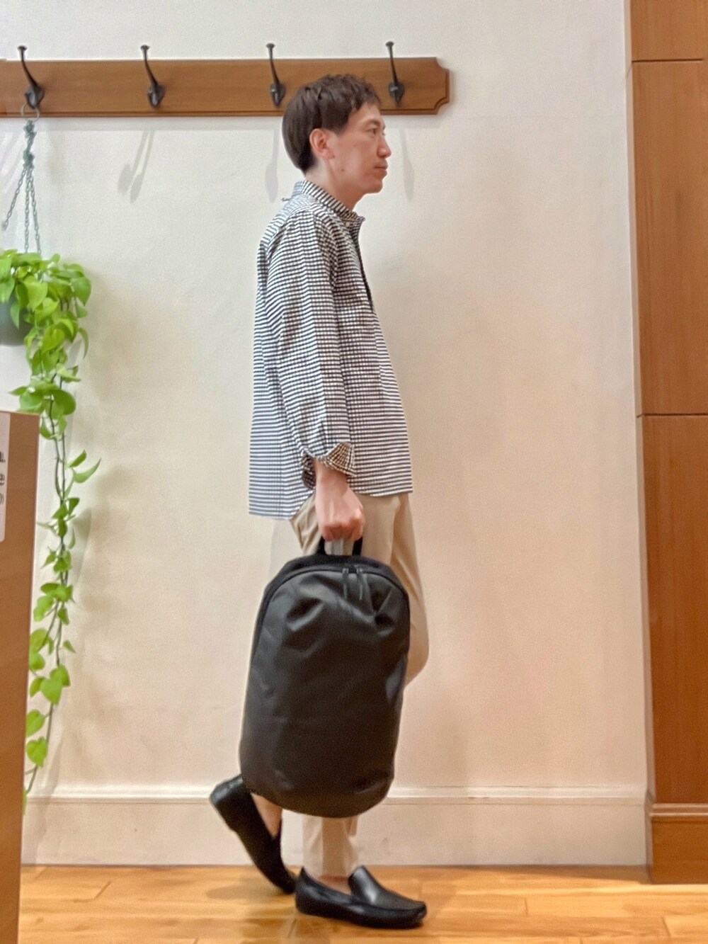 ブラック系のシャツ/ブラウス、グレー系のバックパック/リュック、ベージュ系のチノパンツを着用したメンズの春コーディネートの6枚目の写真