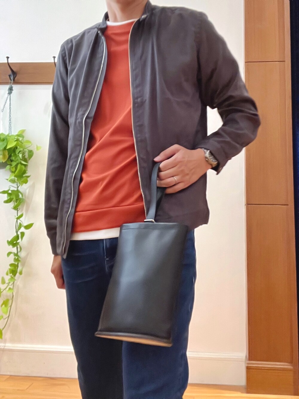 ブルー系のデニムパンツ、ブラック系のハンドバッグ、オレンジ系のTシャツ/カットソーを着用したメンズの秋コーディネートの7枚目の写真