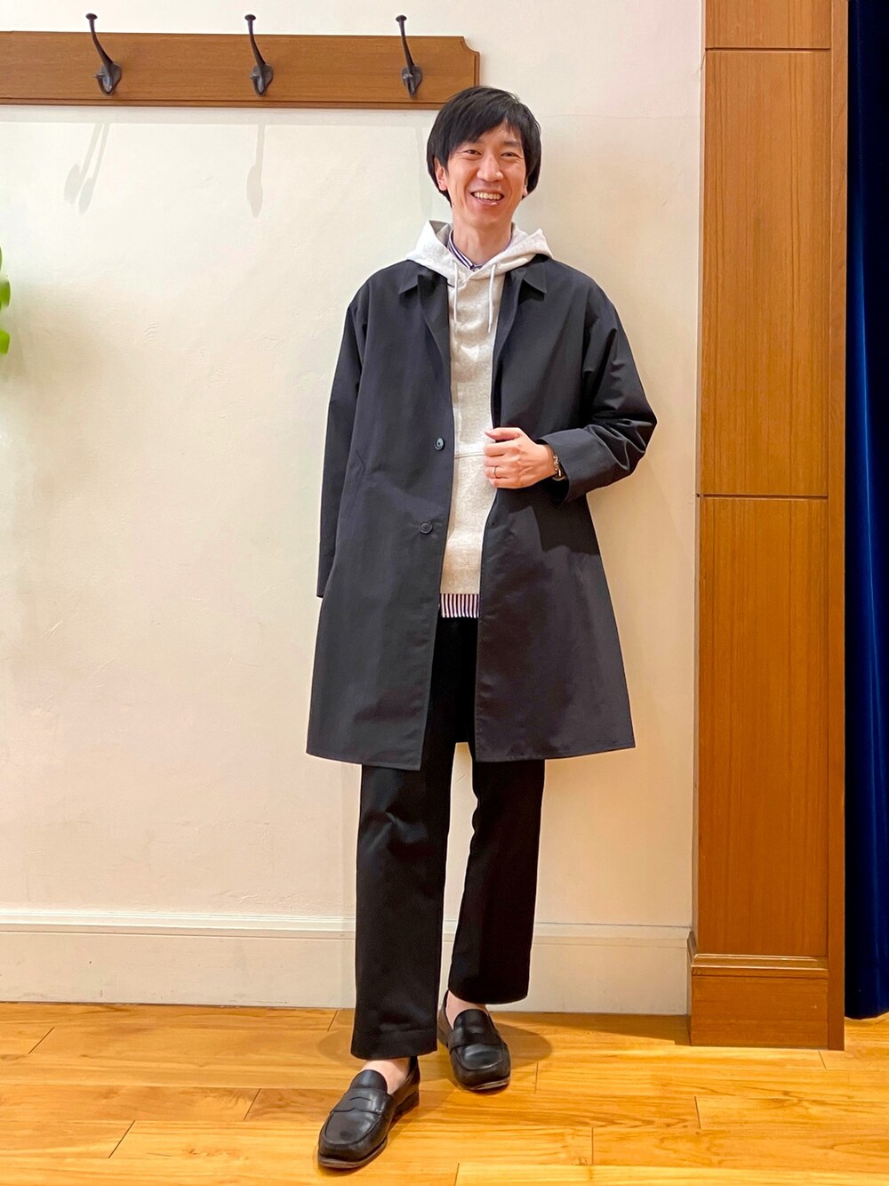 ブラック系のステンカラーコート、グレー系のパーカーを着用したメンズの冬コーディネートの2枚目の写真