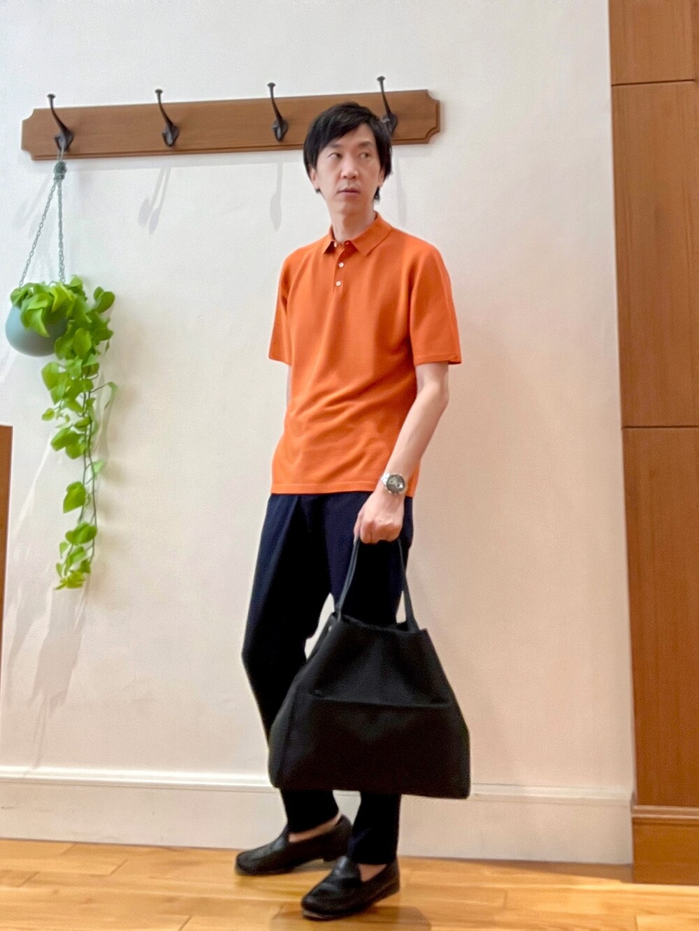オレンジ系のポロシャツ、ブラック系のトートバッグ、ブルー系のその他パンツを着用したメンズの春コーディネートの3枚目の写真