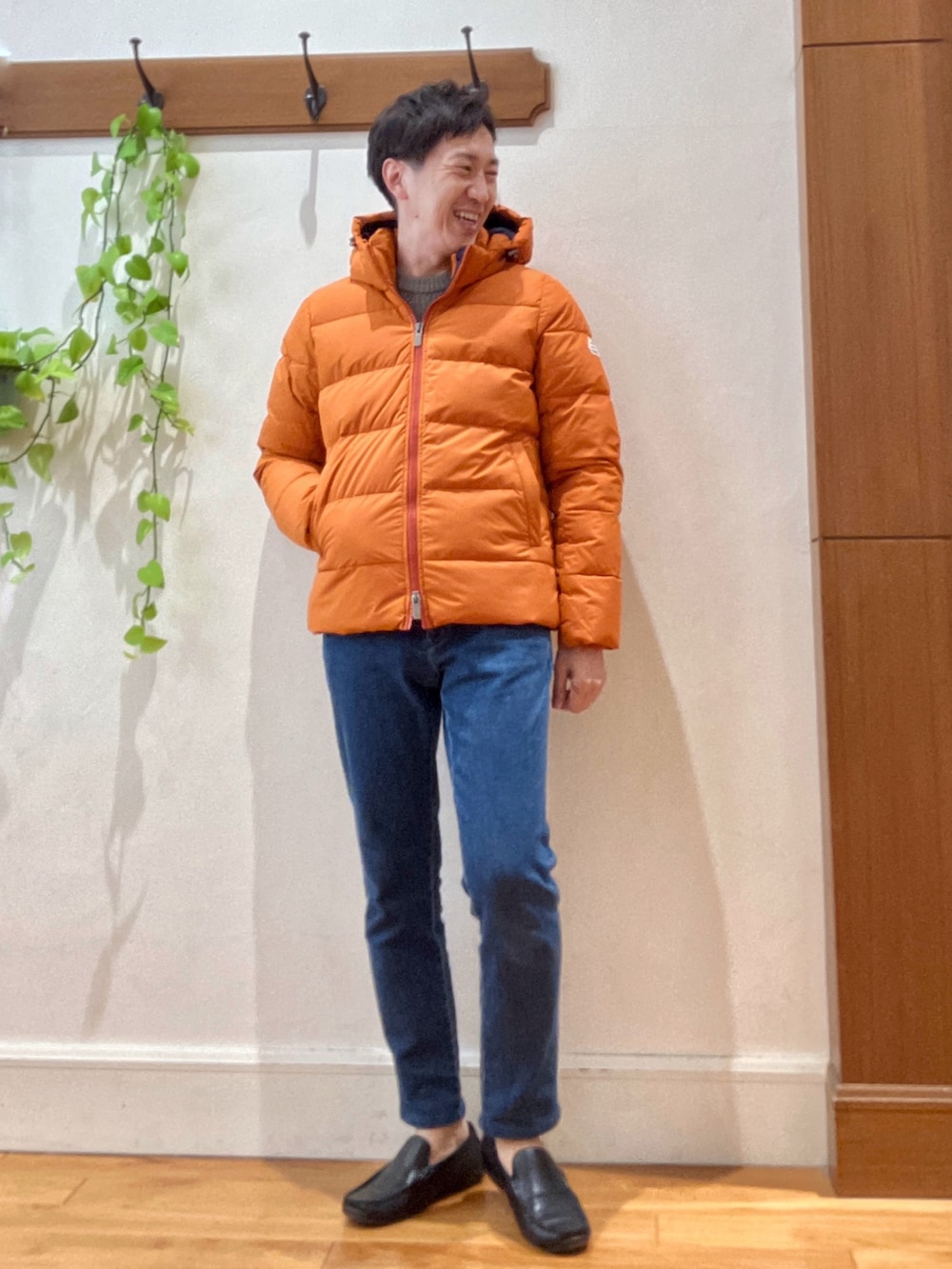 ブルー系のデニムパンツ、ベージュ系のニット/セーター、オレンジ系のダウンジャケット/コートを着用したメンズの冬コーディネートの8枚目の写真