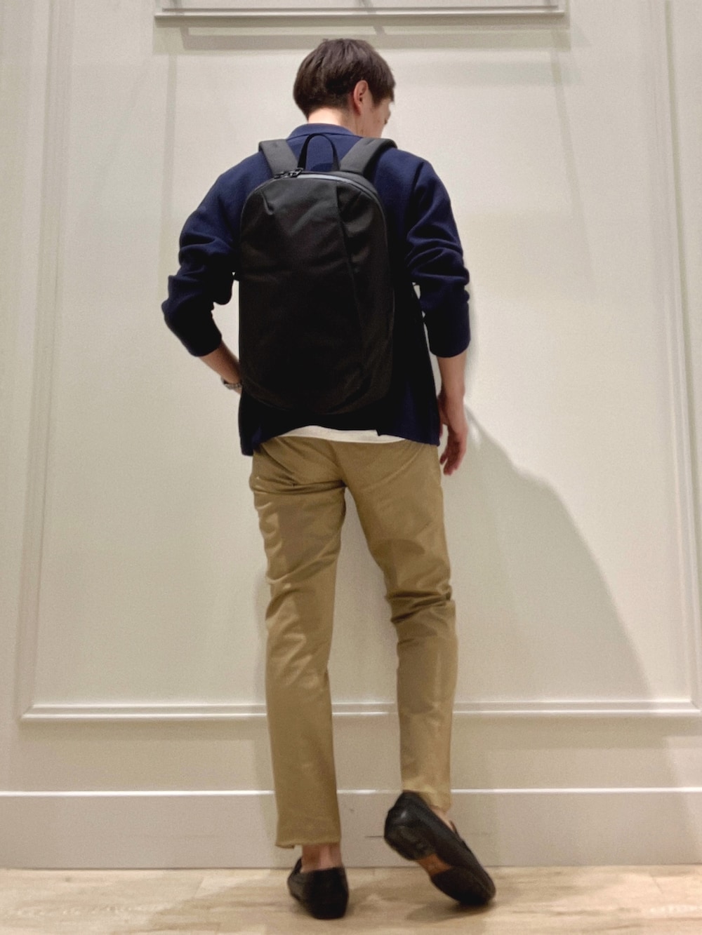 ベージュ系のチノパンツ、ブラック系のバックパック/リュック、ブルー系のカーディガン/ボレロを着用したメンズの冬コーディネートの6枚目の写真