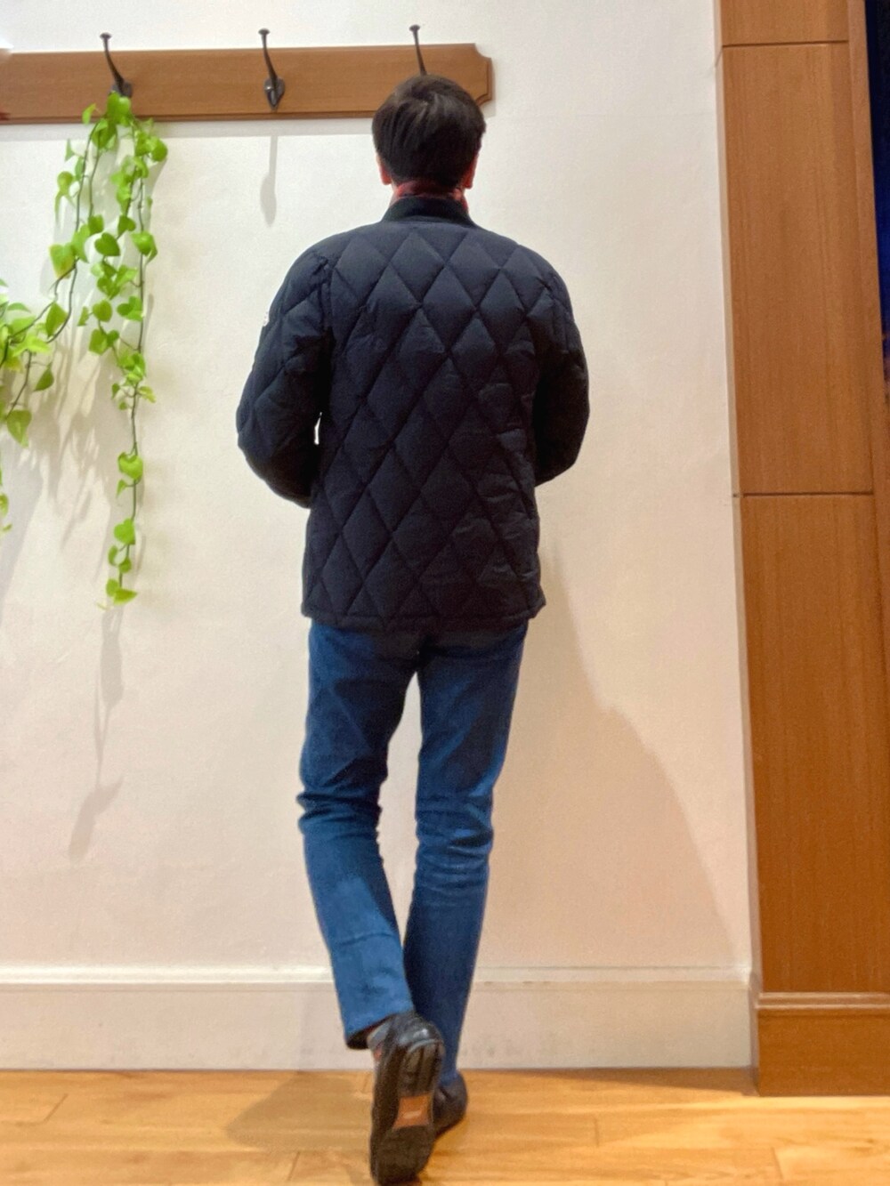 ブラック系のダウンジャケット/コート、ベージュ系のニット/セーター、ブルー系のデニムパンツを着用したメンズの冬コーディネートの4枚目の写真