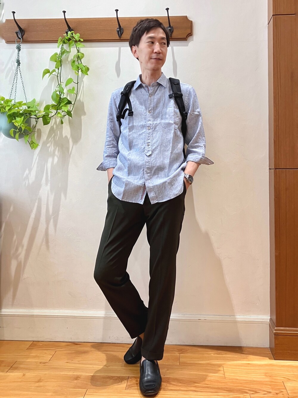 ブルー系のシャツ/ブラウス、ブラウン系のスラックス、ブラック系のバックパック/リュックを着用したメンズの春コーディネートの2枚目の写真