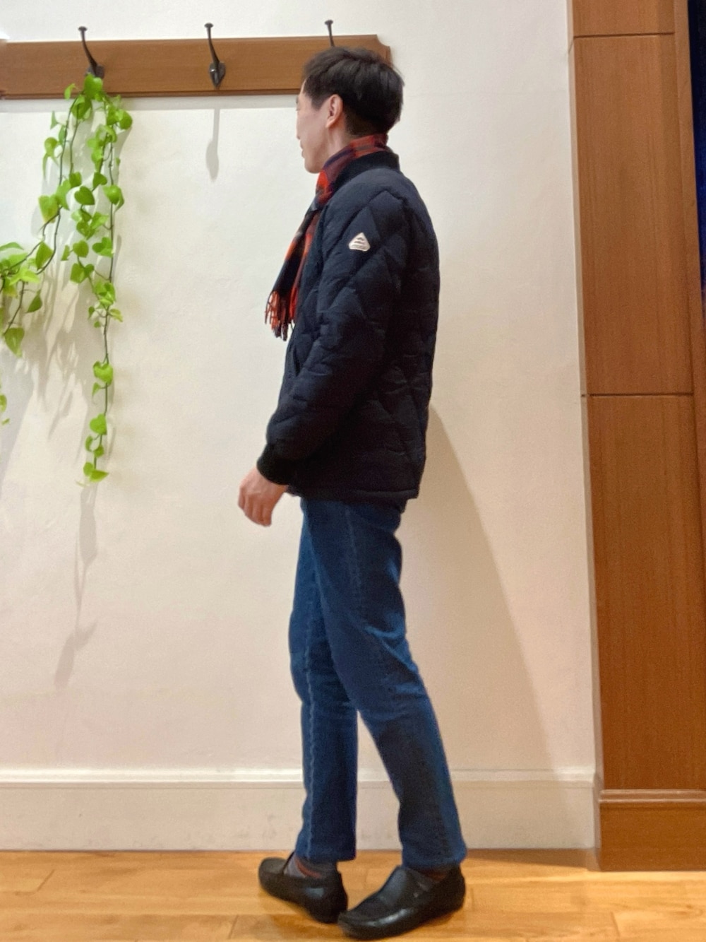 ブラック系のダウンジャケット/コート、ベージュ系のニット/セーター、ブルー系のデニムパンツを着用したメンズの冬コーディネートの3枚目の写真