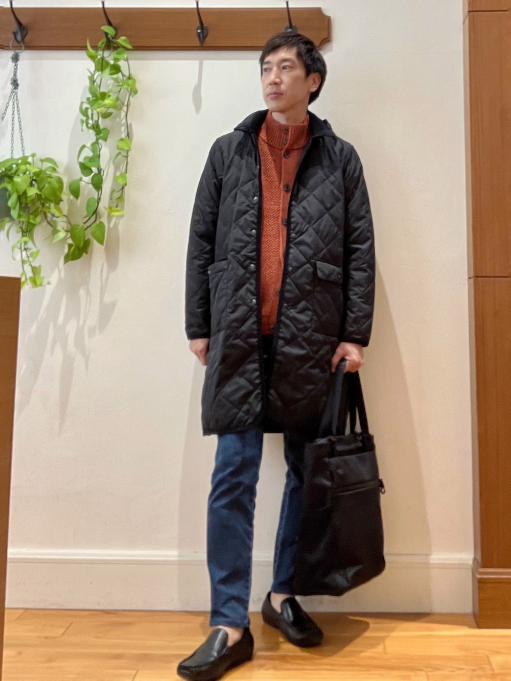 ブラック系のダウンジャケット/コート、オレンジ系のカーディガン/ボレロ、ブラック系のトートバッグを着用したメンズの秋コーディネートの2枚目の写真