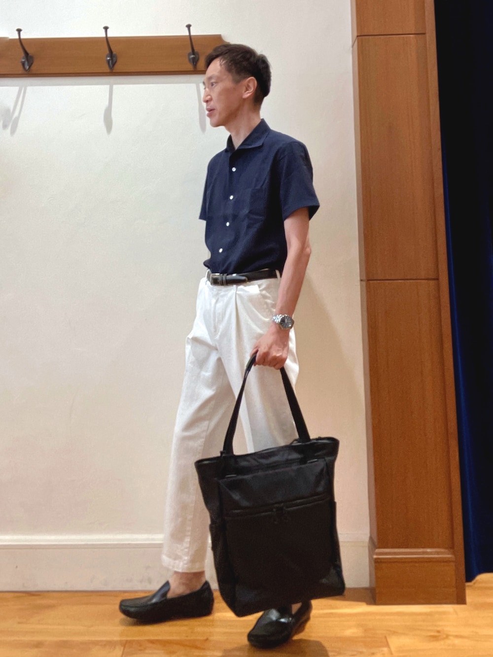ホワイト系のデニムパンツ、ブルー系のビジネスシャツ、ブラック系のトートバッグを着用したメンズの夏コーディネートの3枚目の写真
