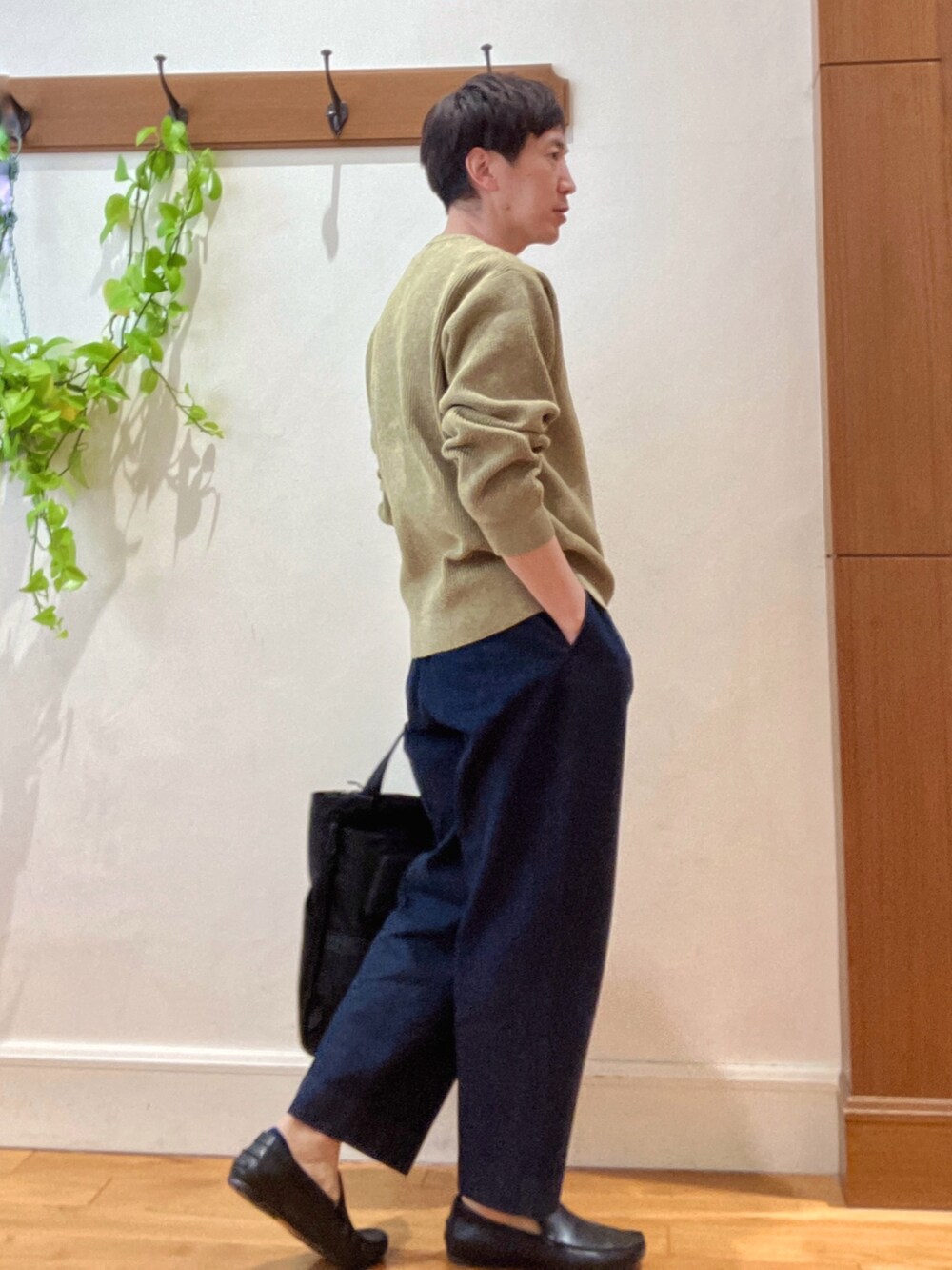イエロー系のニット/セーター、ブルー系のデニムパンツ、ブラック系のトートバッグを着用したメンズの冬コーディネートの6枚目の写真