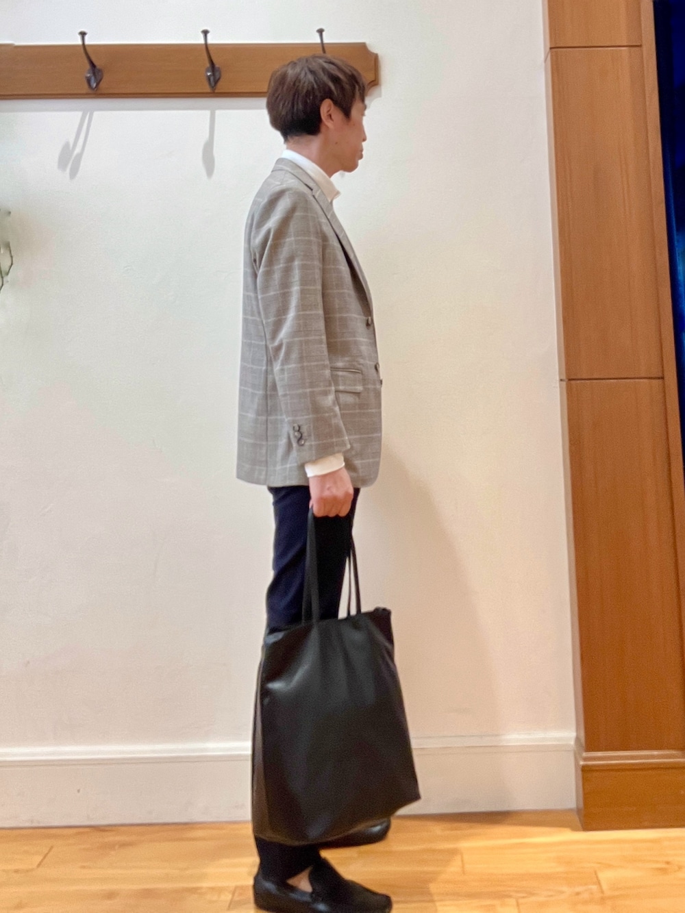 ブラック系のトートバッグ、ブルー系のチノパンツ、ブラウン系のテーラードジャケットを着用したメンズの夏コーディネートの6枚目の写真