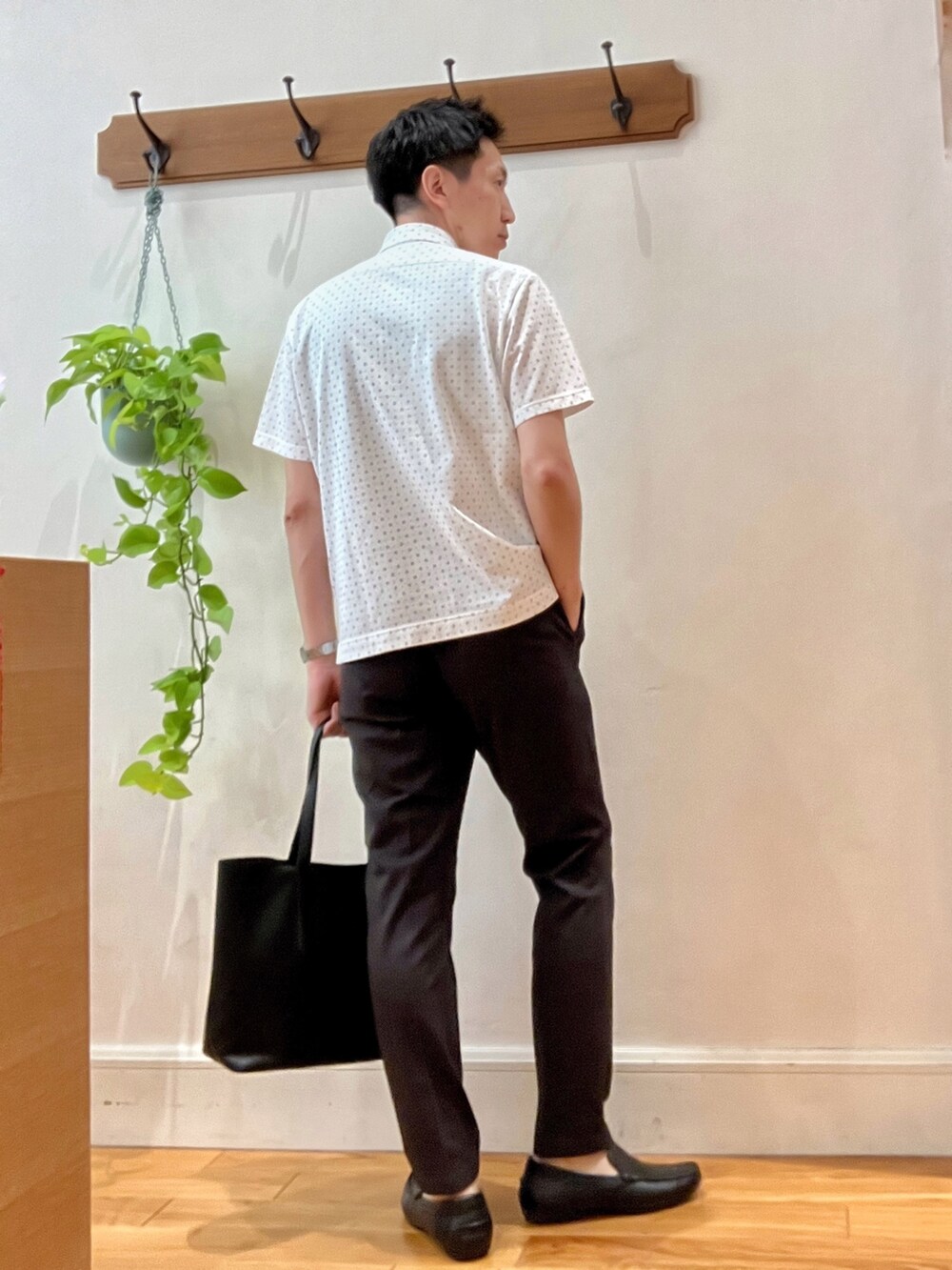 ホワイト系のポロシャツ、ブラック系のトートバッグ、ブラウン系のその他パンツを着用したメンズの夏コーディネートの4枚目の写真