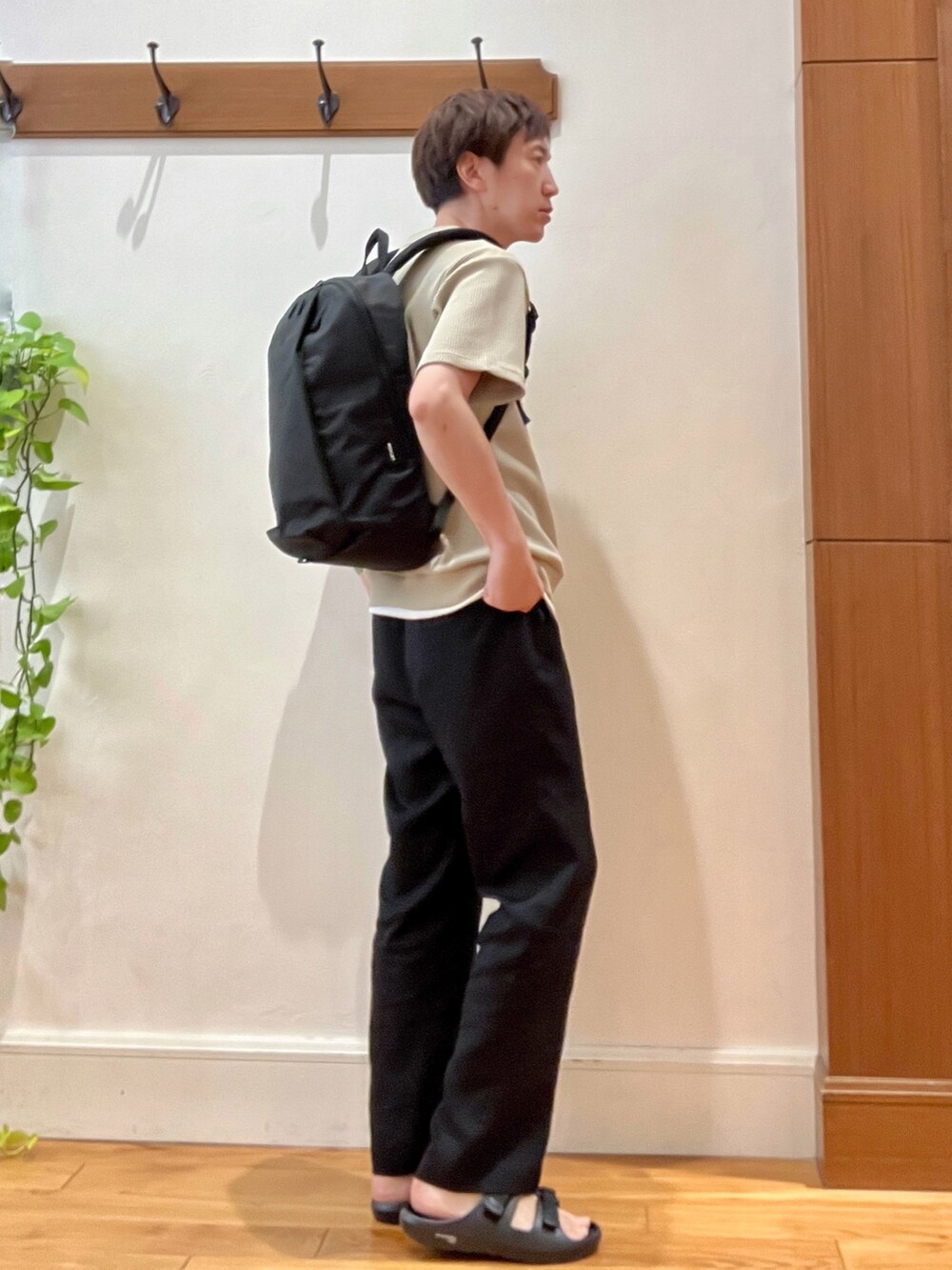 ブラック系のバックパック/リュック、ベージュ系のTシャツ/カットソー、ブラック系のサンダルを着用したメンズの夏コーディネートの5枚目の写真