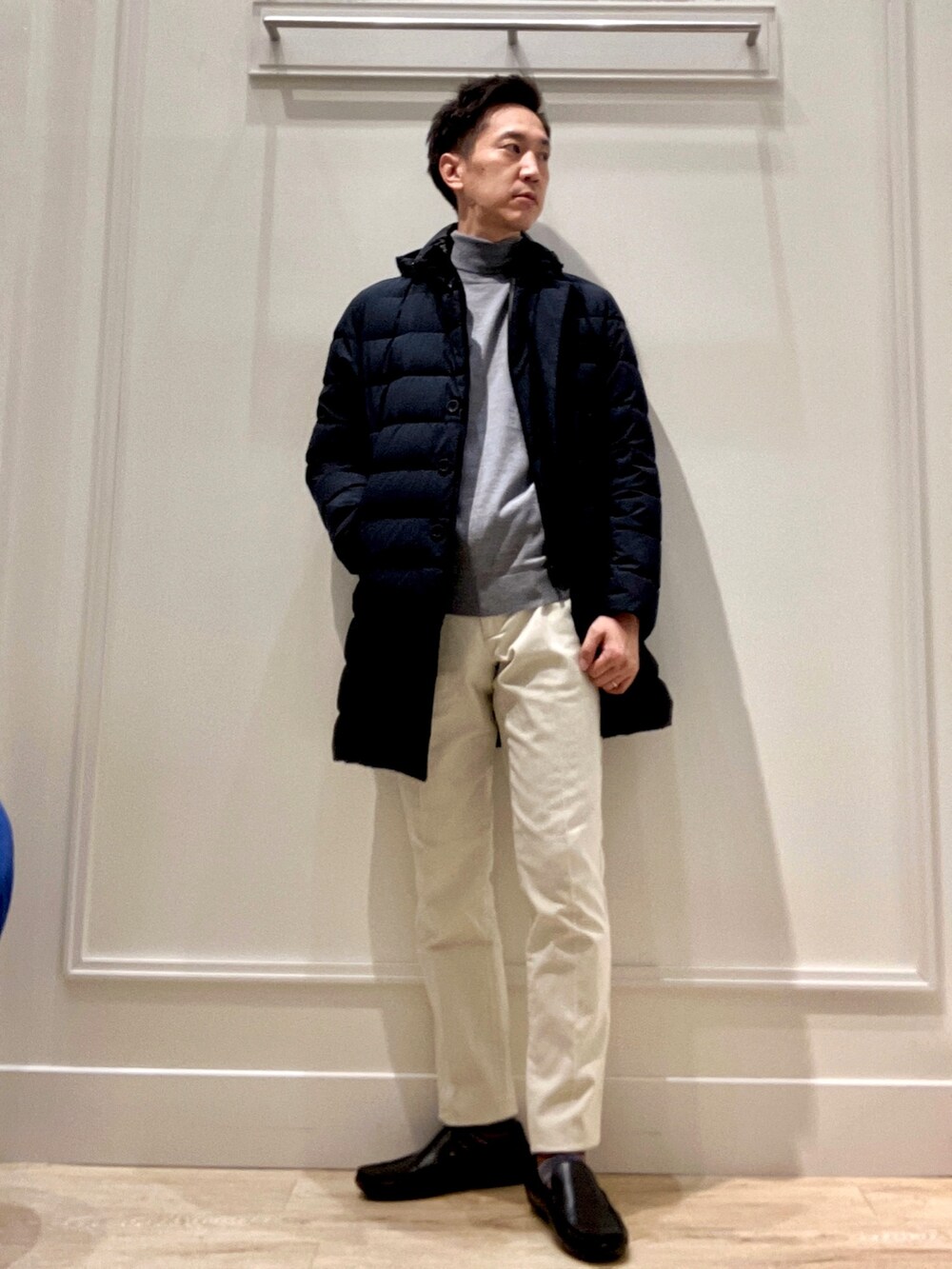 グレー系のニット/セーター、ホワイト系のチノパンツ、ブラック系のダウンジャケット/コートを着用したメンズの秋コーディネートの5枚目の写真