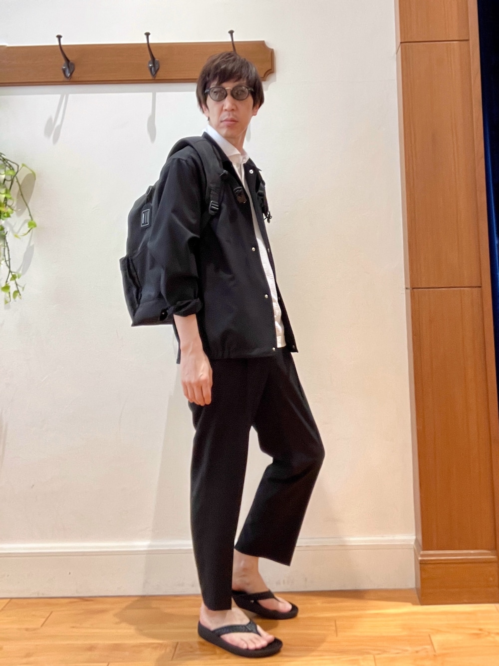 ホワイト系のポロシャツ、ブラック系のサンダル、ブラック系のその他パンツを着用したメンズの春コーディネートの8枚目の写真