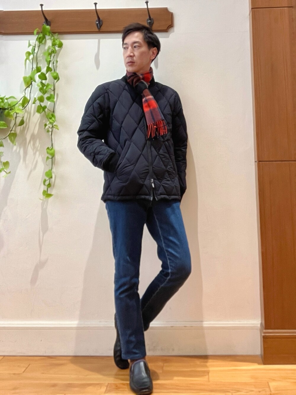 ブラック系のダウンジャケット/コート、ベージュ系のニット/セーター、ブルー系のデニムパンツを着用したメンズの冬コーディネートの6枚目の写真