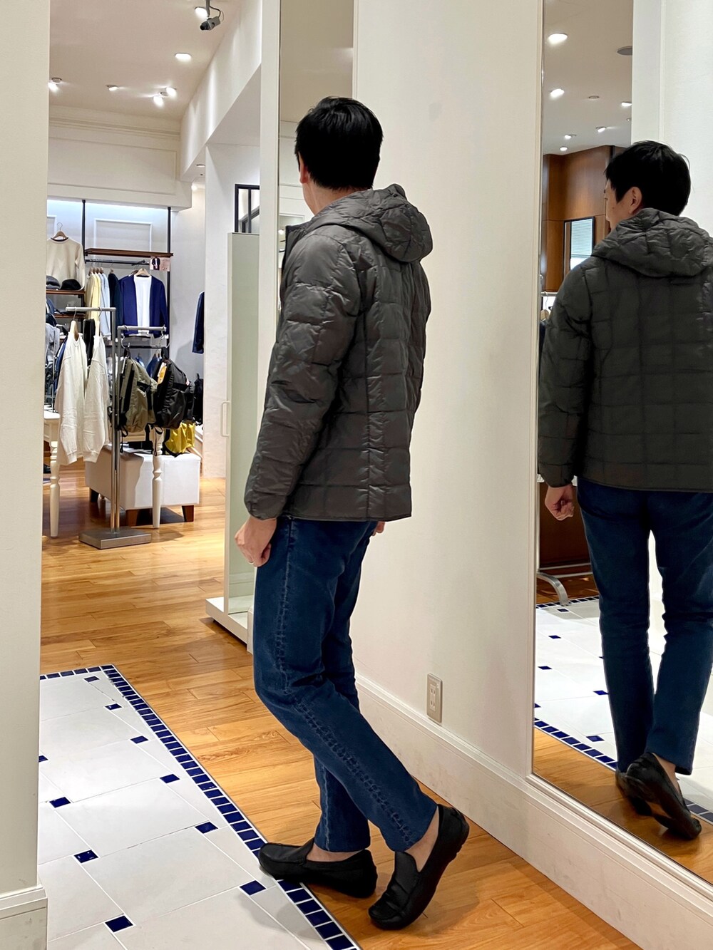 ブルー系のカーディガン/ボレロ、グレー系のダウンジャケット/コート、ブルー系のデニムパンツを着用したメンズの秋コーディネートの4枚目の写真