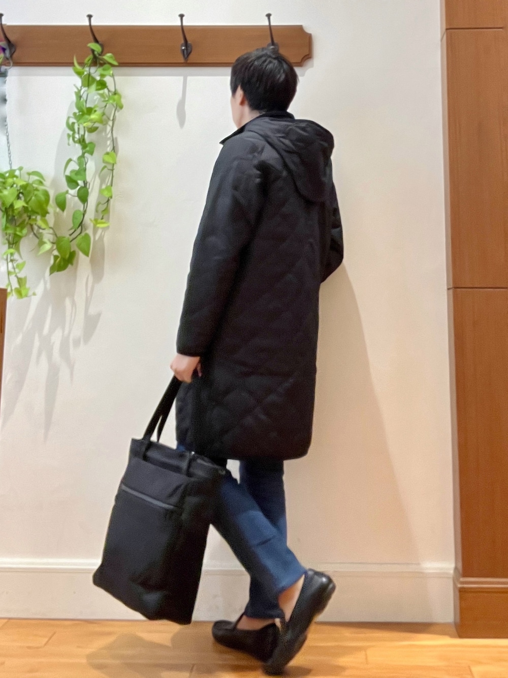 ブラック系のダウンジャケット/コート、オレンジ系のカーディガン/ボレロ、ブラック系のトートバッグを着用したメンズの秋コーディネートの5枚目の写真