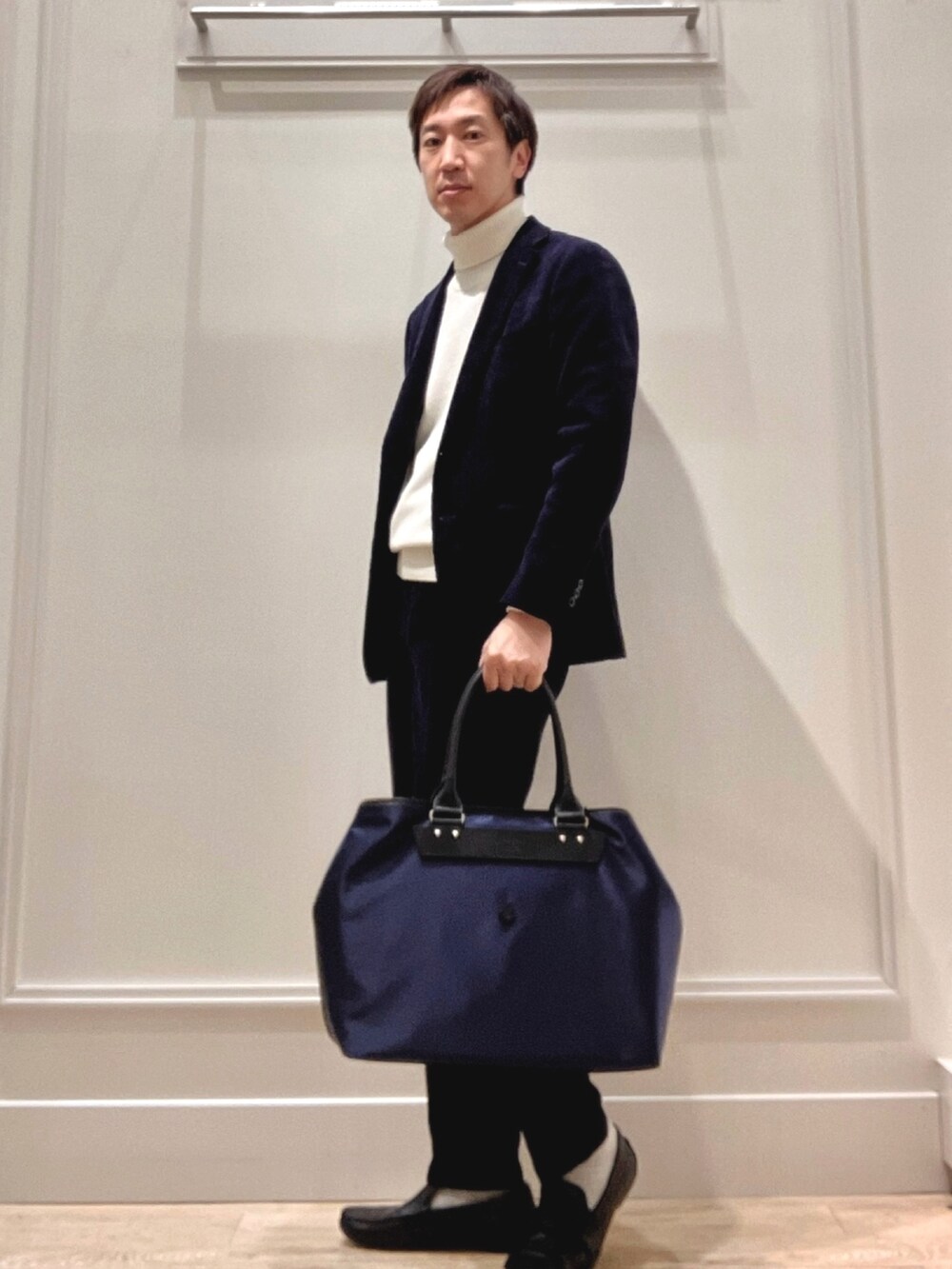 ホワイト系のニット/セーター、ブルー系のトートバッグを着用したメンズの冬コーディネートの3枚目の写真