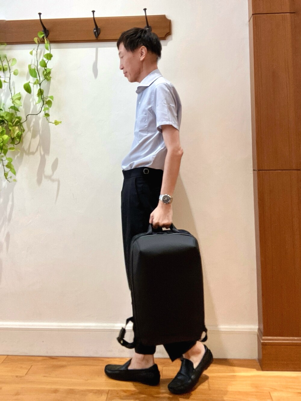 ブラック系のスラックス、ブルー系のビジネスシャツ、ブラック系のバックパック/リュックを着用したメンズの夏コーディネートの2枚目の写真