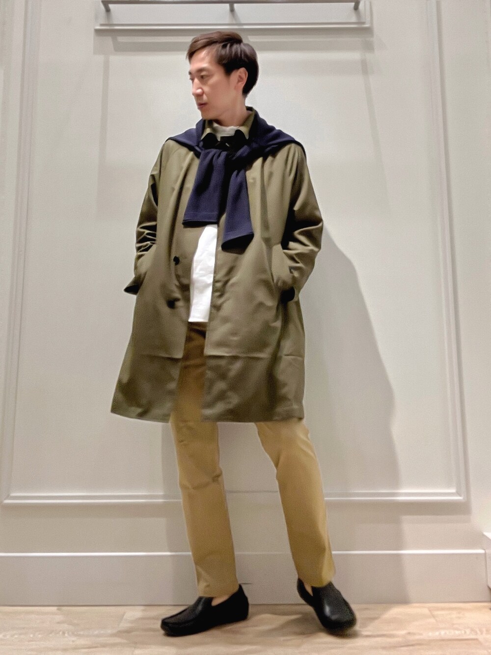 グリーン系のステンカラーコート、ベージュ系のチノパンツ、ブルー系のカーディガン/ボレロを着用したメンズの冬コーディネートの7枚目の写真