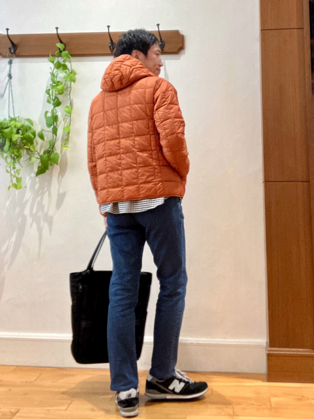 ブラック系のトートバッグ、ブルー系のデニムパンツ、オレンジ系のダウンジャケット/コートを着用したメンズの秋コーディネートの5枚目の写真