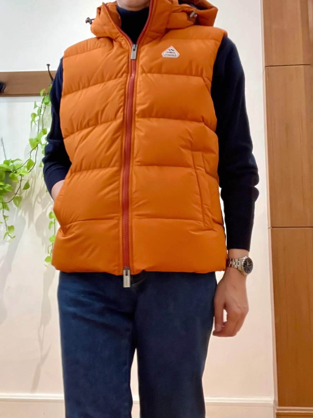 ブルー系のデニムパンツ、ブルー系のニット/セーター、オレンジ系のダウンベストを着用したメンズの冬コーディネートの9枚目の写真