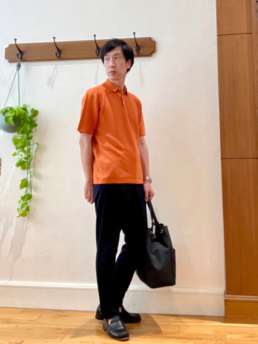 オレンジ系のポロシャツ、ブラック系のトートバッグ、ブルー系のその他パンツを着用したメンズの春コーディネートの5枚目の写真