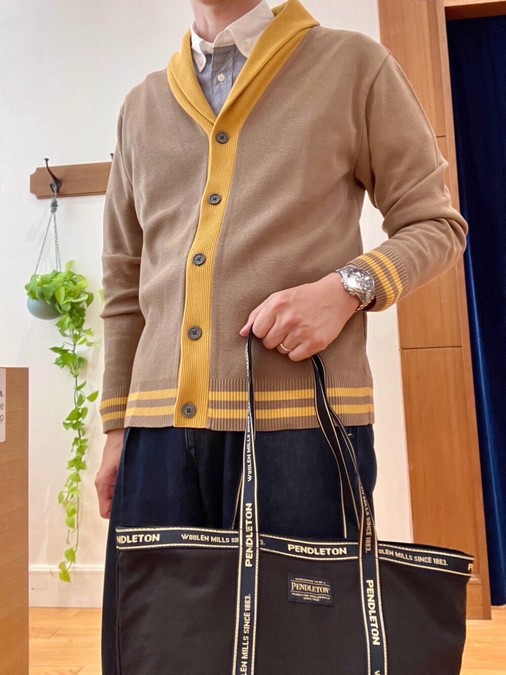 ブルー系のシャツ/ブラウス、ベージュ系のカーディガン/ボレロ、ブラック系のトートバッグを着用したメンズの秋コーディネートの7枚目の写真