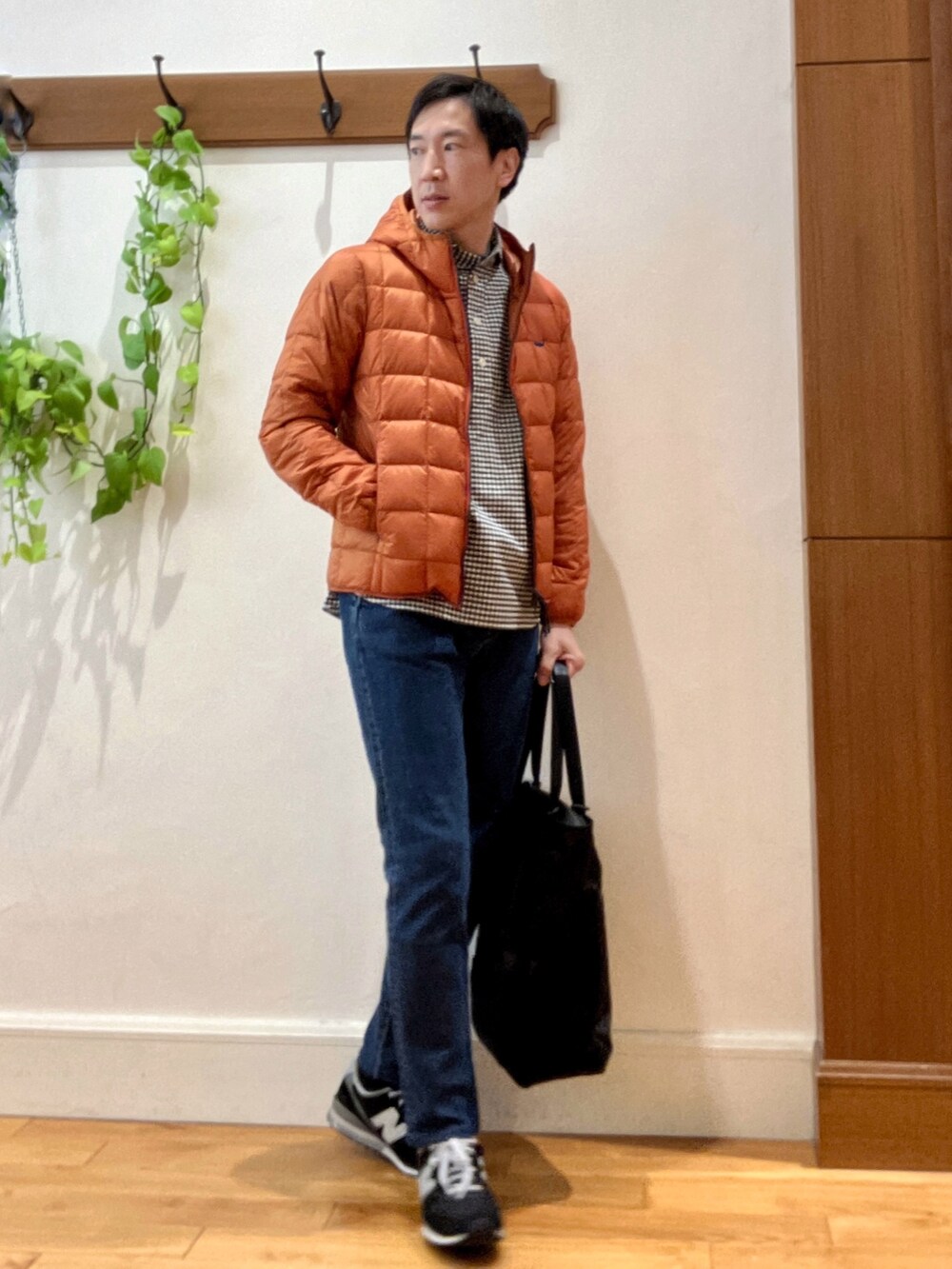 ブラック系のトートバッグ、ブルー系のデニムパンツ、オレンジ系のダウンジャケット/コートを着用したメンズの秋コーディネートの6枚目の写真