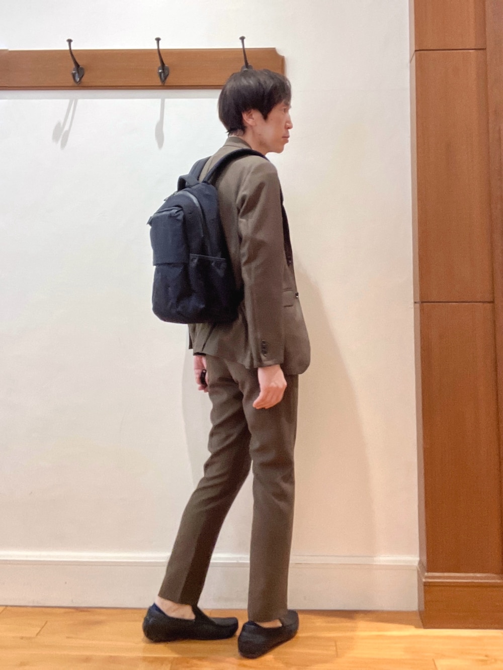 ブラウン系のテーラードジャケット、ブラック系のバックパック/リュック、ブラウン系のその他パンツを着用したメンズの春コーディネートの7枚目の写真