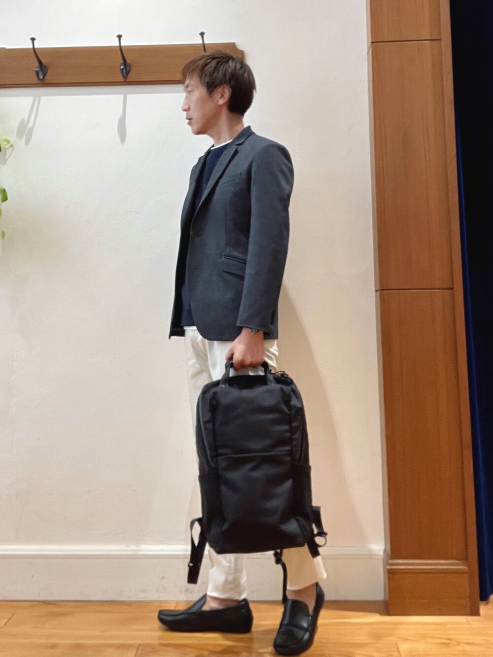 ホワイト系のチノパンツ、ブラック系のバックパック/リュック、ブルー系のテーラードジャケットを着用したメンズの秋コーディネートの2枚目の写真