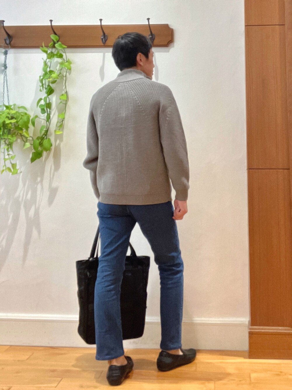 グレー系のニット/セーター、ホワイト系のシャツ/ブラウス、ブルー系のデニムパンツを着用したメンズの秋コーディネートの4枚目の写真