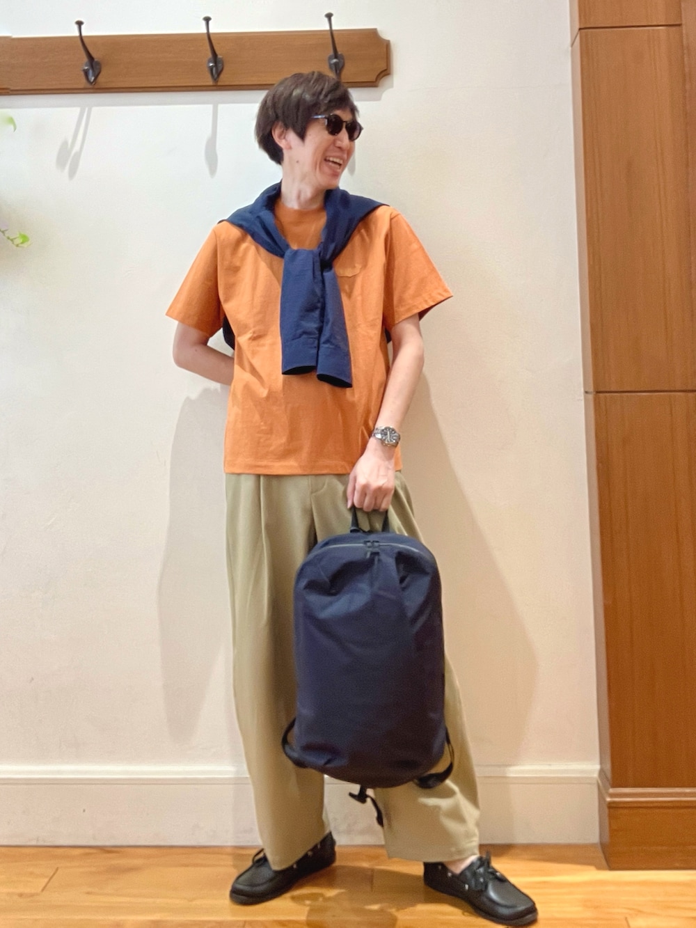 ブラック系のバックパック/リュック、ブルー系のシャツ/ブラウス、オレンジ系のTシャツ/カットソーを着用したメンズの春コーディネートの2枚目の写真