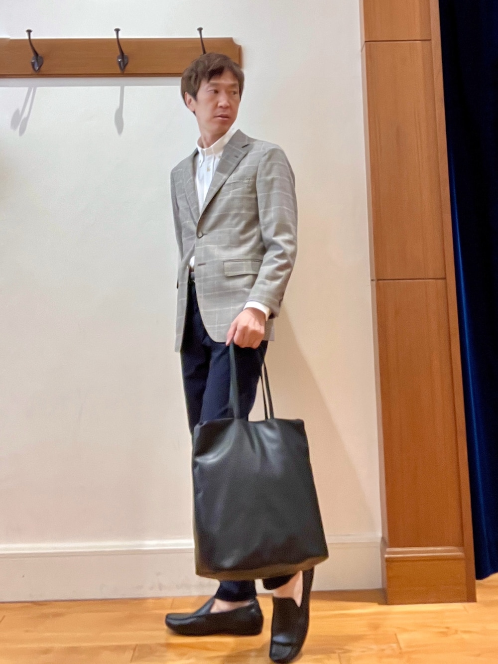 ブラック系のトートバッグ、ブルー系のチノパンツ、ブラウン系のテーラードジャケットを着用したメンズの夏コーディネートの3枚目の写真
