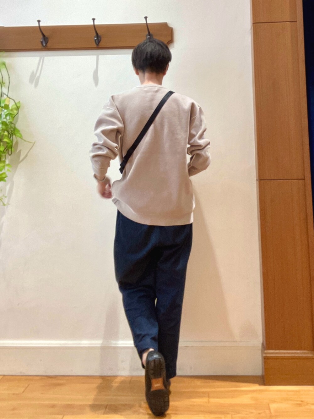 ブルー系のデニムパンツ、ブラック系のショルダーバッグ、ベージュ系のニット/セーターを着用したメンズの秋コーディネートの4枚目の写真