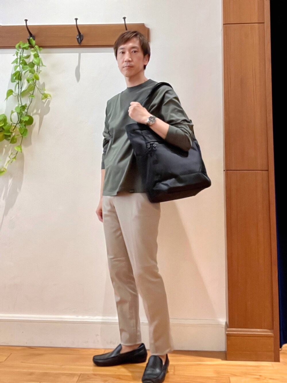 グリーン系のTシャツ/カットソー、グレー系のチノパンツ、ブラック系のトートバッグを着用したメンズの秋コーディネートの7枚目の写真