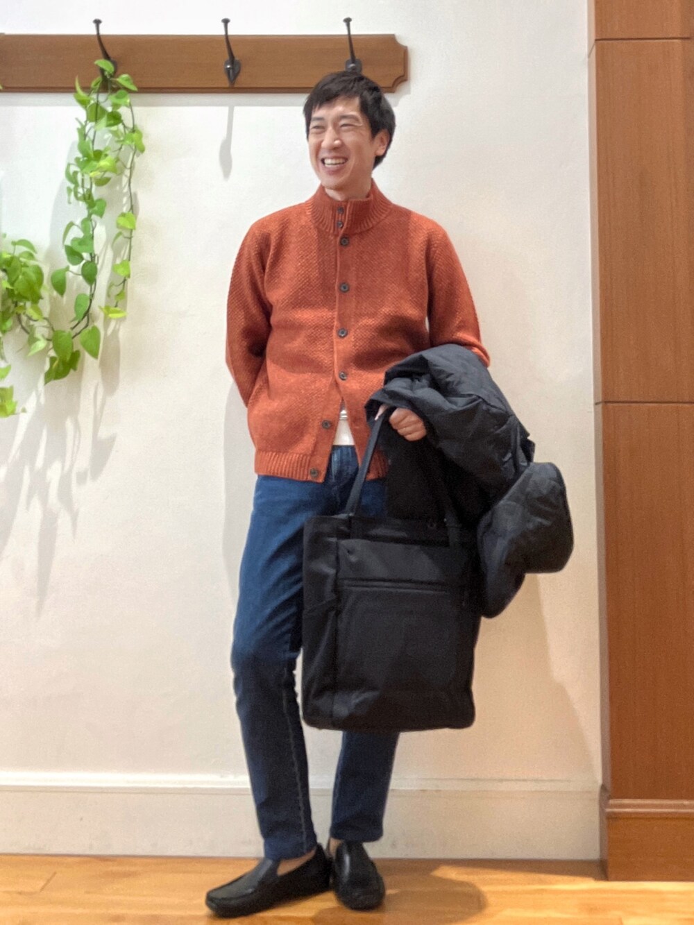 ブラック系のダウンジャケット/コート、オレンジ系のカーディガン/ボレロ、ブラック系のトートバッグを着用したメンズの秋コーディネートの8枚目の写真