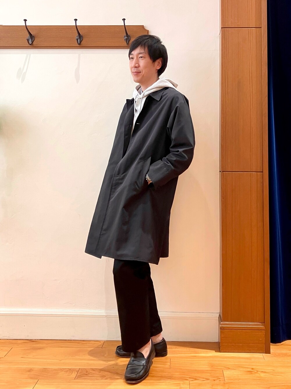 ブラック系のステンカラーコート、グレー系のパーカーを着用したメンズの冬コーディネートの3枚目の写真