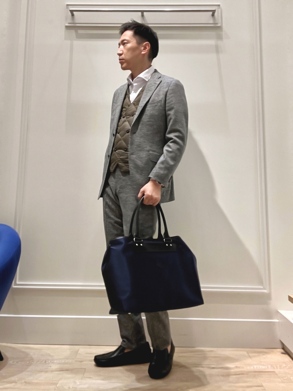 グレー系のテーラードジャケット、グレー系のスラックス、ブラック系のトートバッグを着用したメンズの秋コーディネートの2枚目の写真
