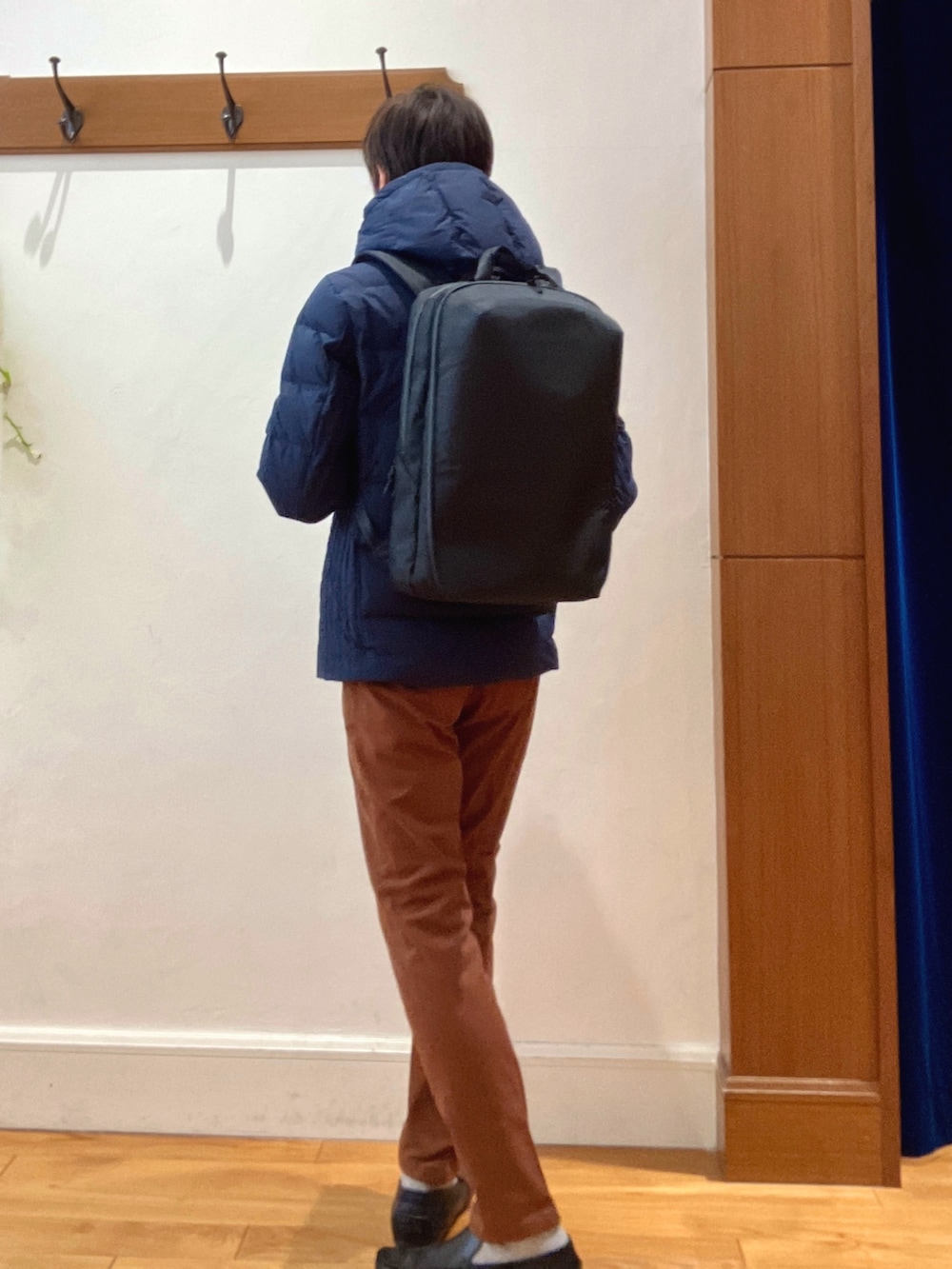 ブルー系のダウンジャケット/コート、イエロー系のチノパンツ、ブラック系のバックパック/リュックを着用したメンズの冬コーディネートの4枚目の写真