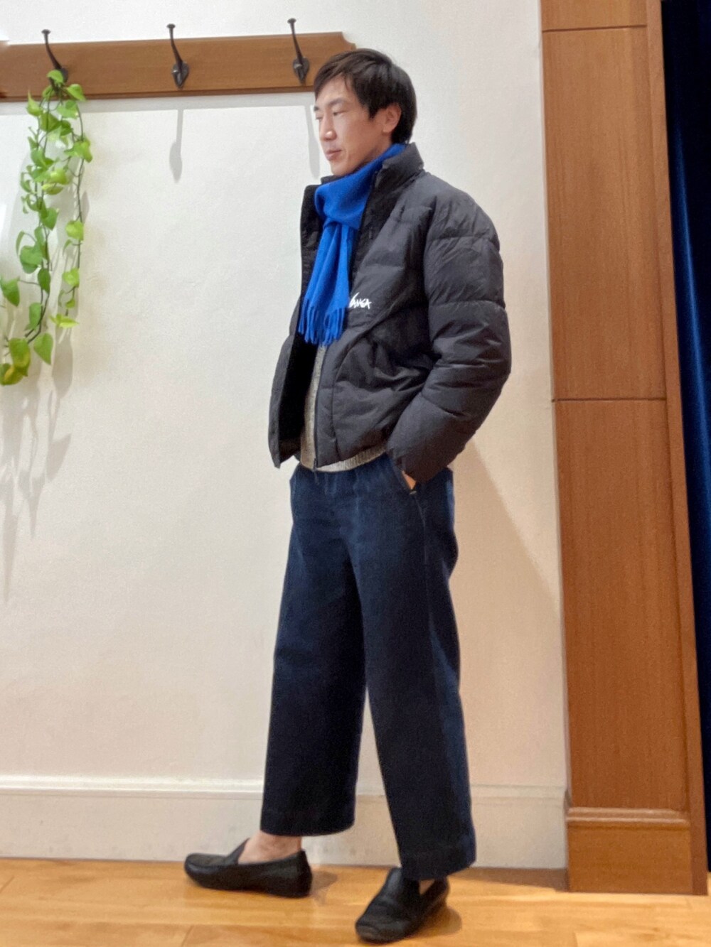 グリーン系のダウンジャケット/コート、ブルー系のニット/セーター、ブルー系のマフラーを着用したメンズの秋コーディネートの3枚目の写真