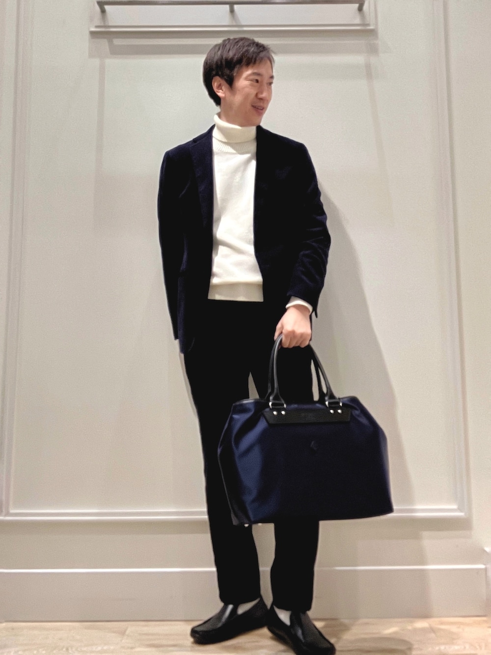 ホワイト系のニット/セーター、ブルー系のトートバッグを着用したメンズの冬コーディネートの2枚目の写真