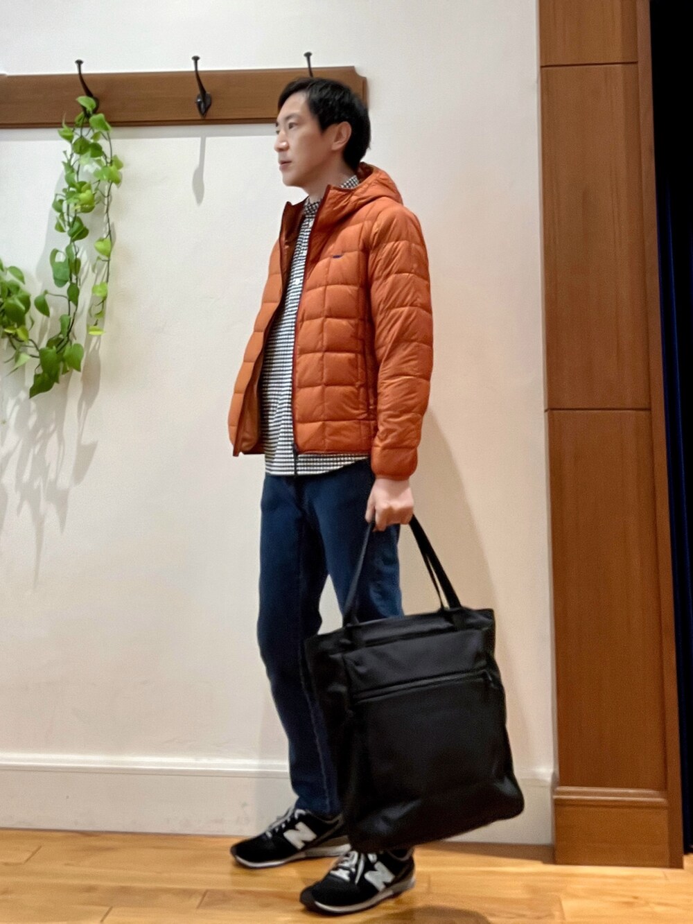 ブラック系のトートバッグ、ブルー系のデニムパンツ、オレンジ系のダウンジャケット/コートを着用したメンズの秋コーディネートの3枚目の写真