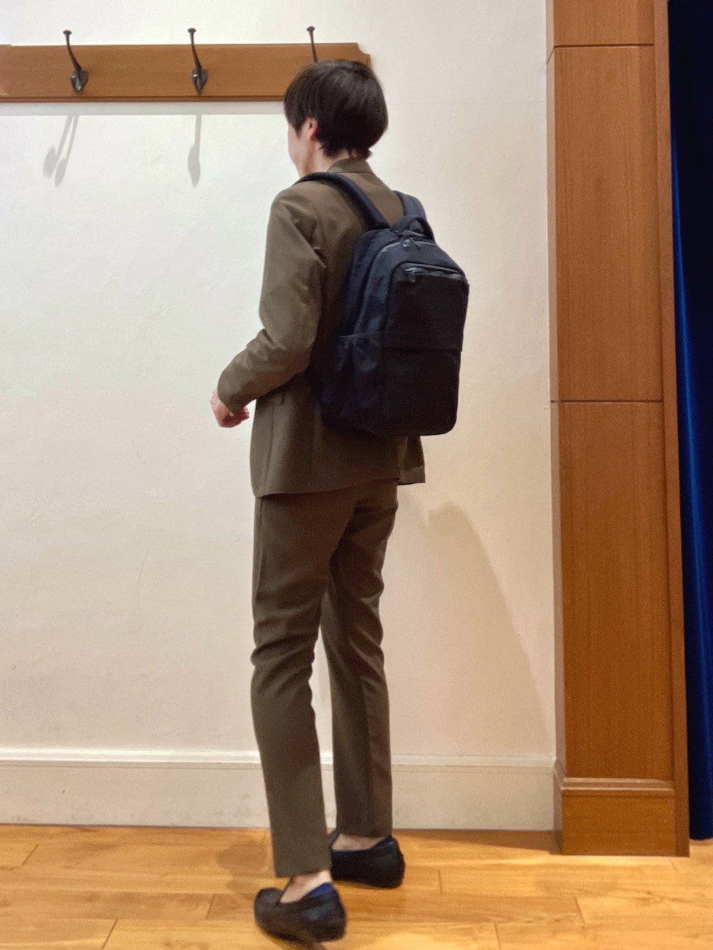 ブラウン系のテーラードジャケット、ブラック系のバックパック/リュック、ブラウン系のその他パンツを着用したメンズの春コーディネートの3枚目の写真