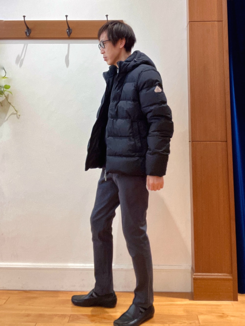 グレー系のチノパンツ、ブラック系のニット/セーター、ブラック系のダウンジャケット/コートを着用したメンズの冬コーディネートの2枚目の写真