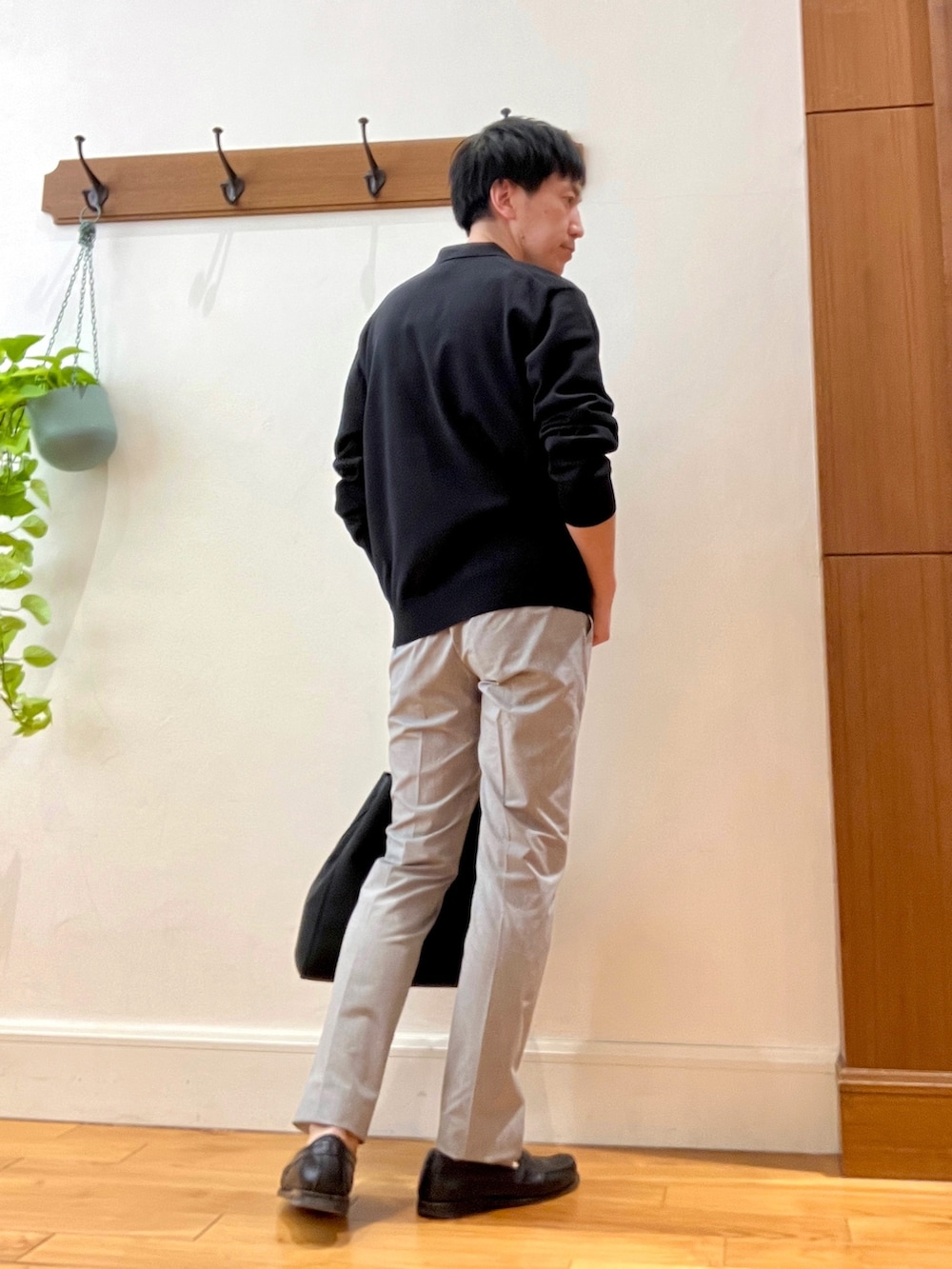ブラック系のニット/セーター、ベージュ系のその他パンツ、ブラック系のトートバッグを着用したメンズの春コーディネートの6枚目の写真