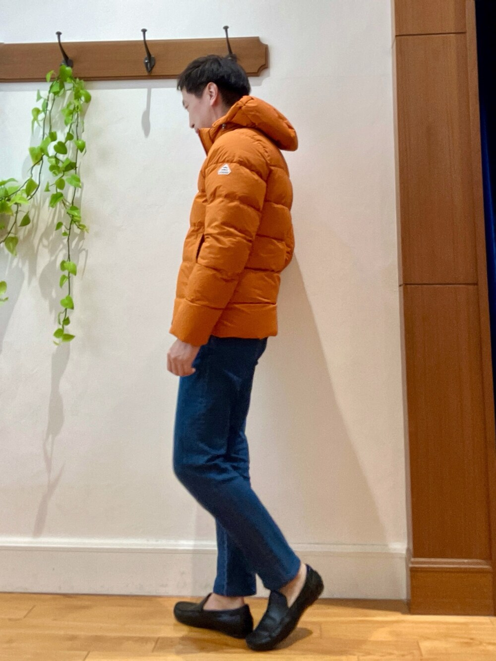 ブルー系のデニムパンツ、ベージュ系のニット/セーター、オレンジ系のダウンジャケット/コートを着用したメンズの冬コーディネートの4枚目の写真